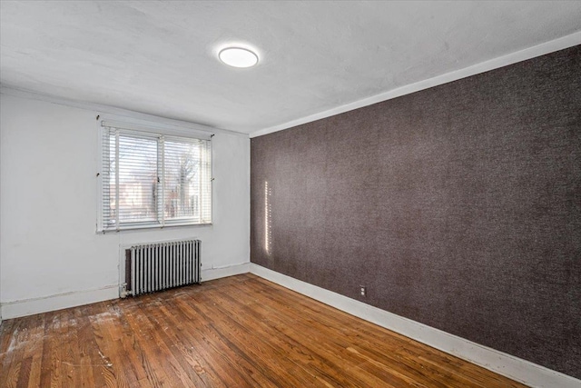 spare room featuring dark hardwood / wood-style flooring and radiator