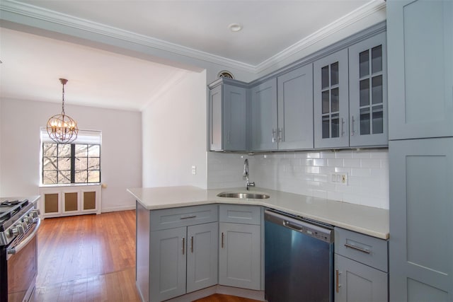 kitchen with sink, tasteful backsplash, light wood-type flooring, appliances with stainless steel finishes, and pendant lighting