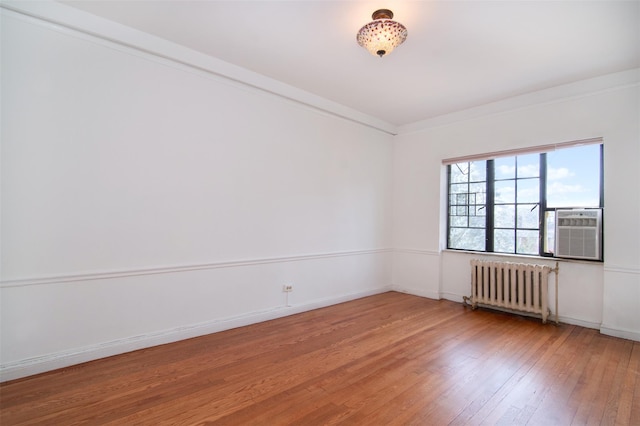 spare room featuring radiator heating unit, ornamental molding, and wood-type flooring