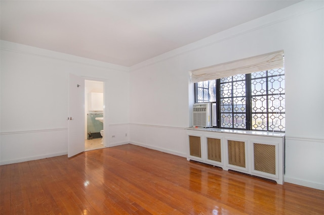 unfurnished room with wood-type flooring, radiator, and ornamental molding