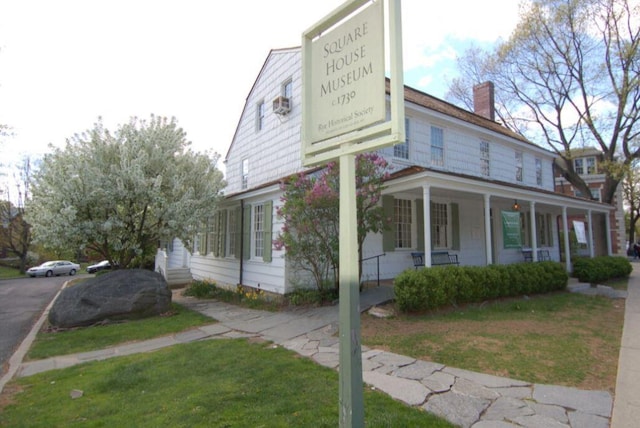 view of side of property with a porch and a lawn