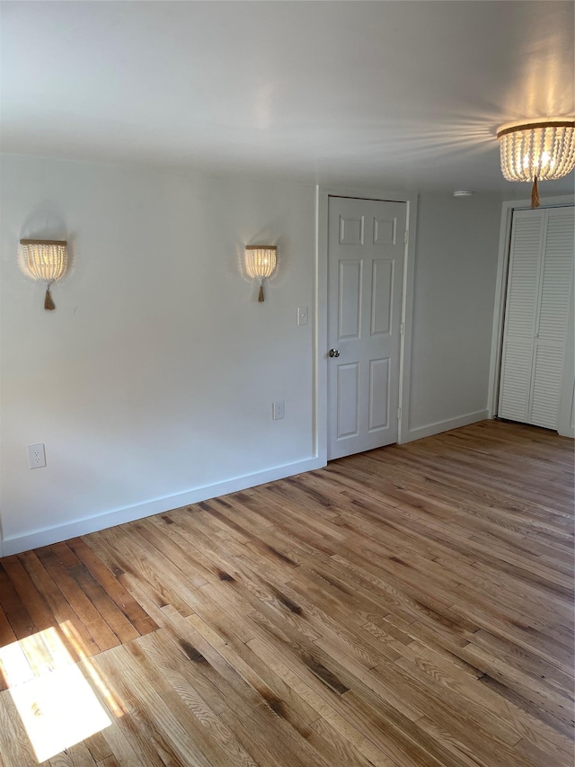 unfurnished room featuring an inviting chandelier and wood-type flooring