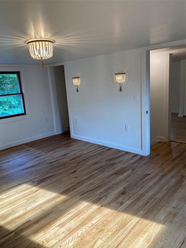 spare room featuring an inviting chandelier and light wood-type flooring