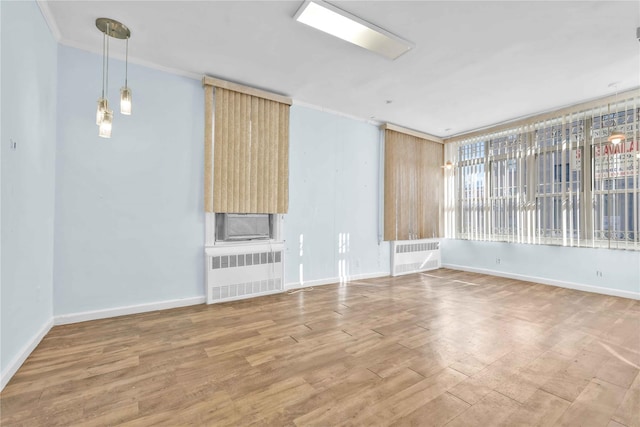 unfurnished living room featuring ornamental molding, radiator, and hardwood / wood-style floors