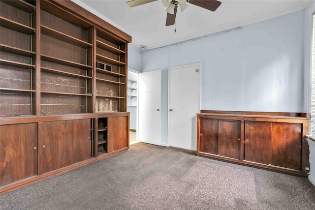 unfurnished living room with ceiling fan and dark colored carpet