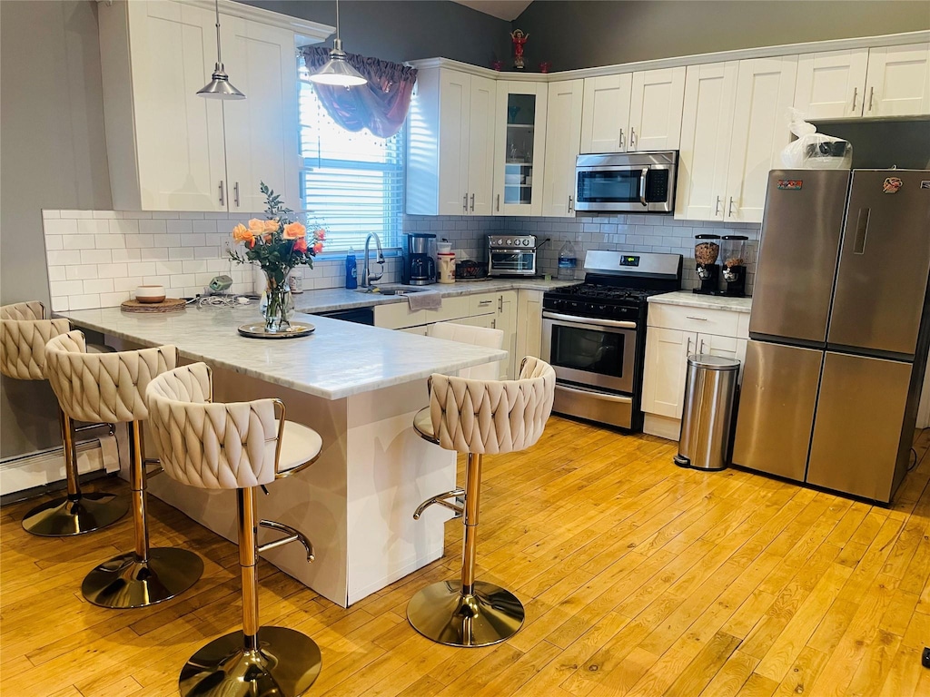 kitchen featuring appliances with stainless steel finishes, white cabinets, a kitchen bar, and kitchen peninsula