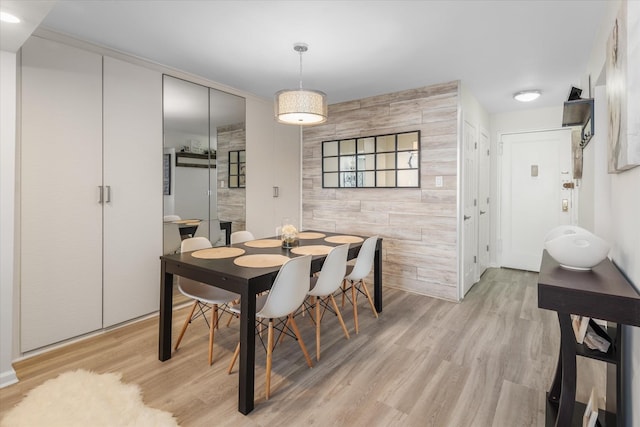 dining area with wooden walls and light wood-type flooring