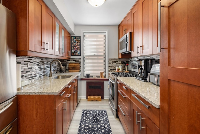 kitchen featuring tasteful backsplash, appliances with stainless steel finishes, light stone countertops, and sink