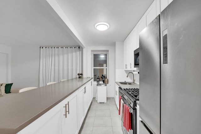 kitchen with light tile patterned flooring, sink, white cabinets, decorative backsplash, and stainless steel appliances