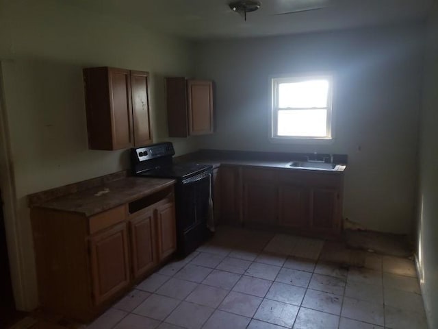 kitchen featuring black electric range oven, sink, and light tile patterned floors