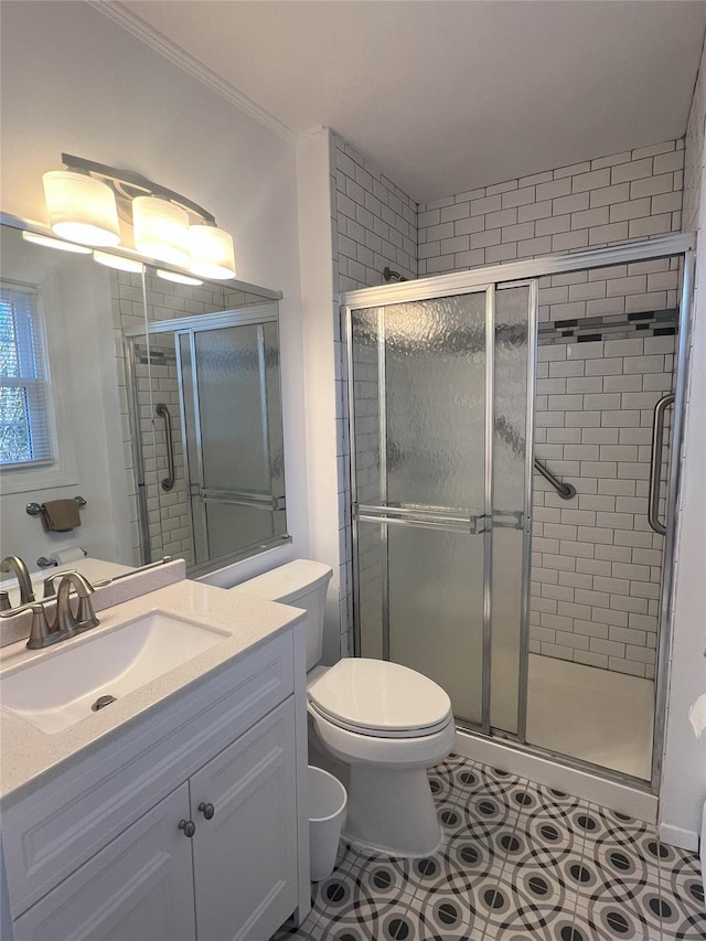 bathroom with vanity, ornamental molding, a shower with shower door, tile patterned floors, and toilet