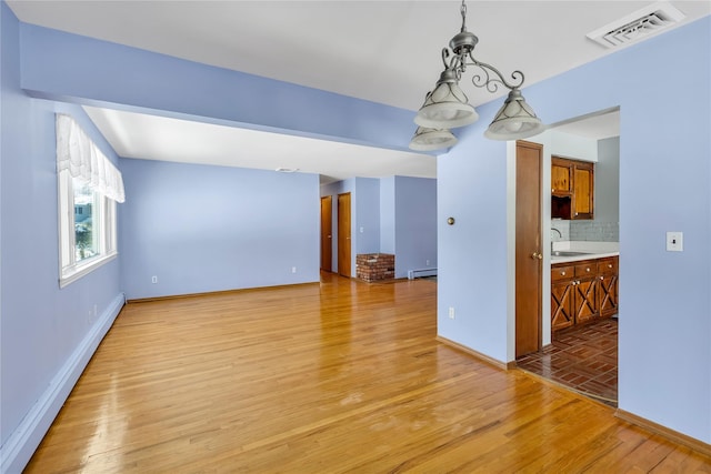 interior space featuring sink, baseboard heating, and light wood-type flooring