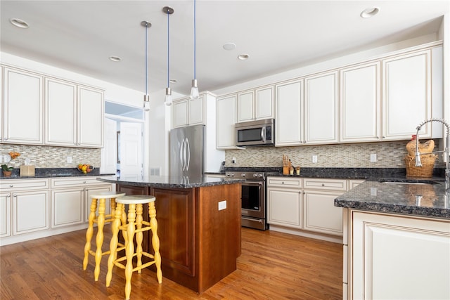 kitchen with sink, a breakfast bar area, a kitchen island, pendant lighting, and stainless steel appliances