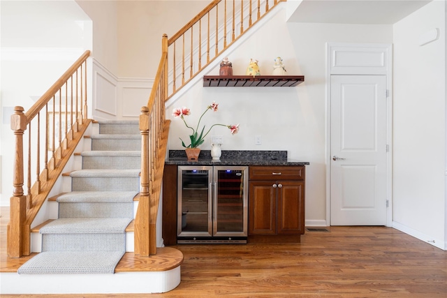 bar with dark hardwood / wood-style floors, beverage cooler, and dark stone countertops