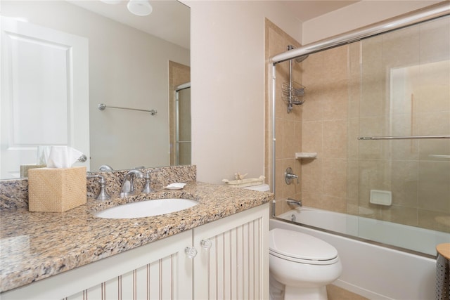 full bathroom with vanity, bath / shower combo with glass door, and toilet