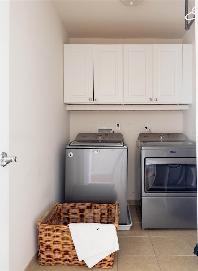 laundry room with cabinets, light tile patterned floors, and washer and clothes dryer