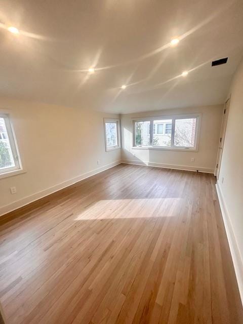 empty room with a wealth of natural light, light hardwood / wood-style flooring, and vaulted ceiling