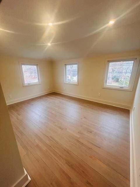 unfurnished room featuring a healthy amount of sunlight, lofted ceiling, and hardwood / wood-style floors