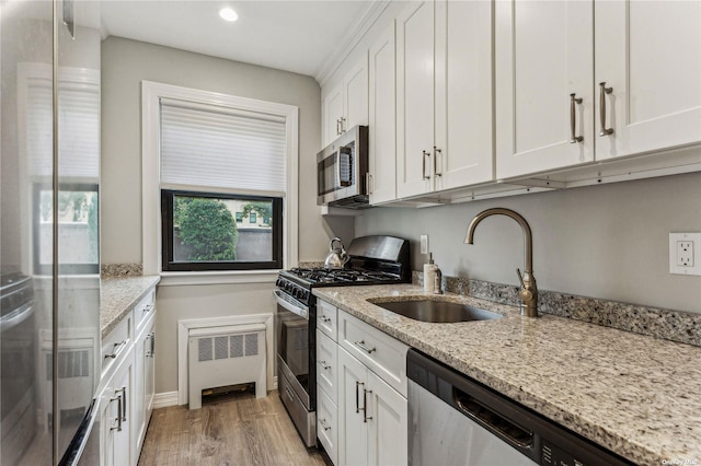 kitchen with stainless steel appliances, light stone countertops, sink, and white cabinets