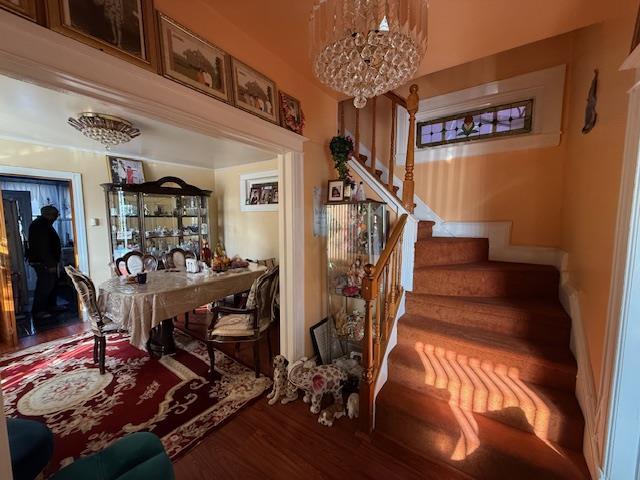 staircase with a chandelier and hardwood / wood-style floors