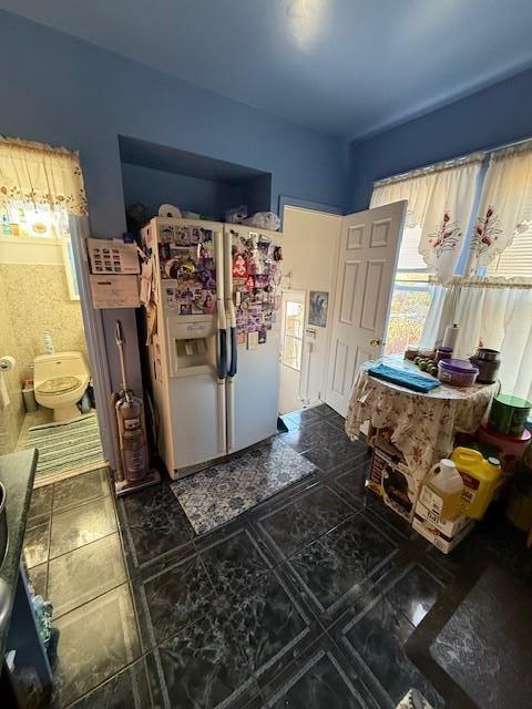 bedroom with connected bathroom and white refrigerator with ice dispenser