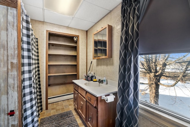 bathroom featuring a baseboard radiator, a wealth of natural light, a drop ceiling, and vanity