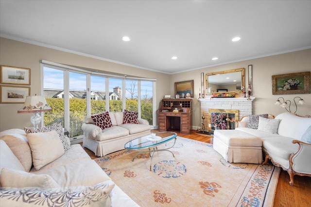 living room featuring hardwood / wood-style flooring, a stone fireplace, and ornamental molding