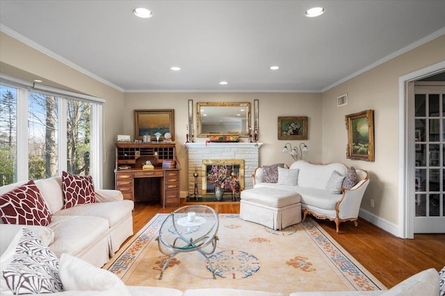 living room with hardwood / wood-style floors, a fireplace, and ornamental molding