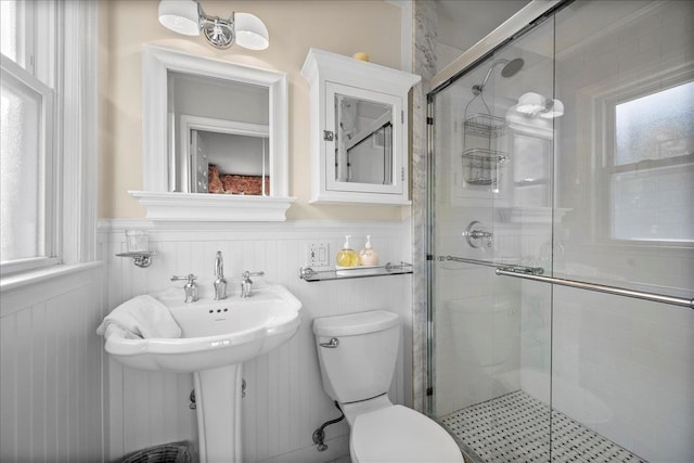 bathroom featuring sink, plenty of natural light, toilet, and a shower with door