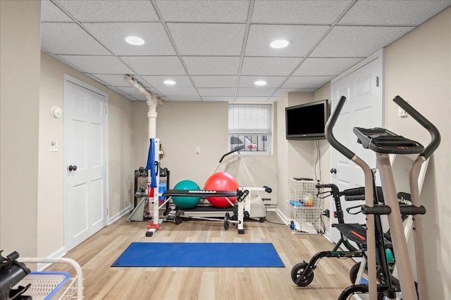 exercise room with a paneled ceiling and wood-type flooring