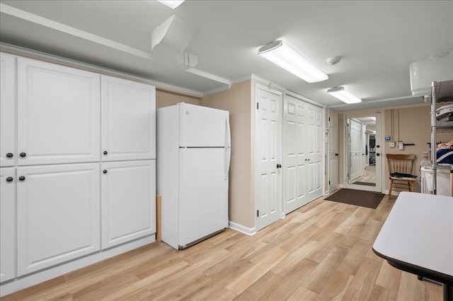 kitchen featuring white refrigerator, white cabinetry, crown molding, and light hardwood / wood-style flooring