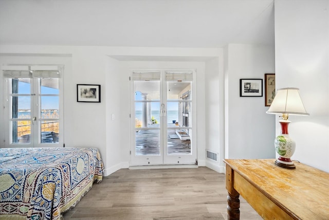 bedroom featuring multiple windows, access to outside, french doors, and wood-type flooring