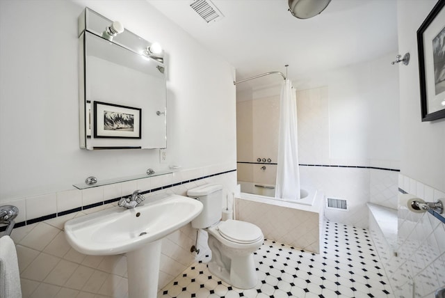 bathroom featuring tile walls, shower / tub combo, tile patterned floors, and toilet