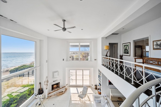 living room featuring plenty of natural light, light tile patterned flooring, a high ceiling, and a water view