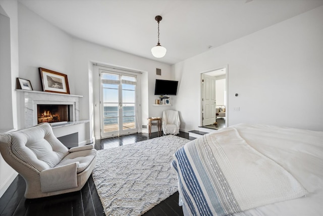 bedroom featuring access to exterior, dark hardwood / wood-style flooring, and a fireplace