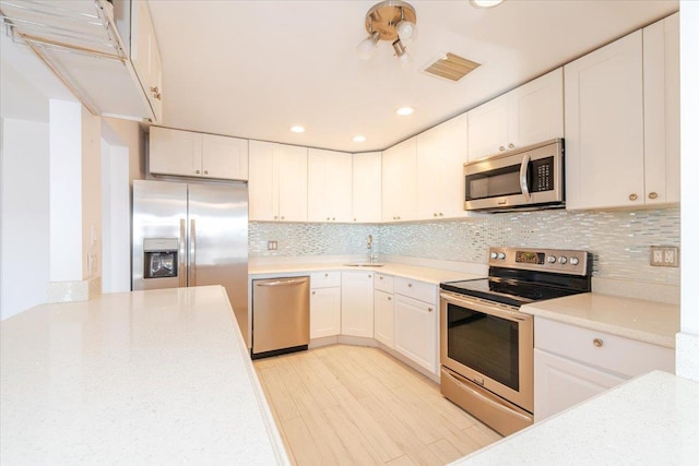 kitchen featuring sink, decorative backsplash, white cabinets, and appliances with stainless steel finishes