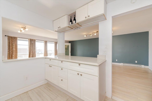 kitchen with a baseboard heating unit, kitchen peninsula, light wood-type flooring, and white cabinets