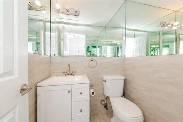 bathroom with vanity, toilet, and tile walls