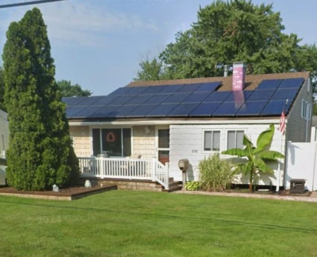 view of front of house featuring a front lawn and solar panels