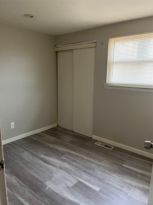 unfurnished bedroom featuring dark hardwood / wood-style flooring and a closet