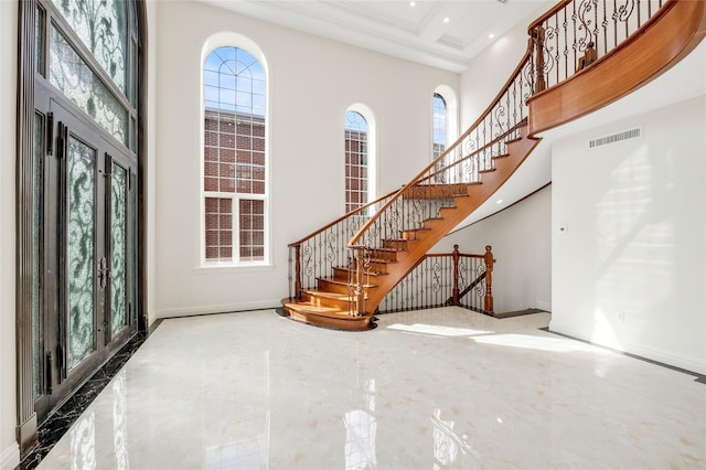 entrance foyer with a high ceiling, crown molding, a wealth of natural light, and french doors