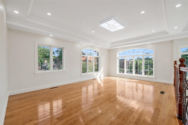 unfurnished living room featuring crown molding, light hardwood / wood-style flooring, and a tray ceiling