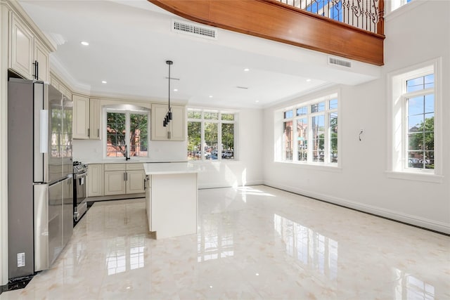 kitchen featuring a kitchen island, appliances with stainless steel finishes, pendant lighting, and cream cabinets