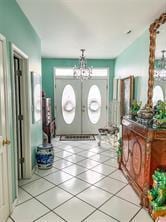 foyer featuring tile patterned flooring, a notable chandelier, and french doors