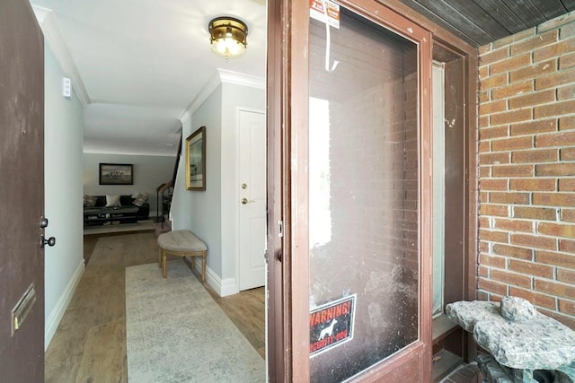 hallway with crown molding, brick wall, and light hardwood / wood-style floors