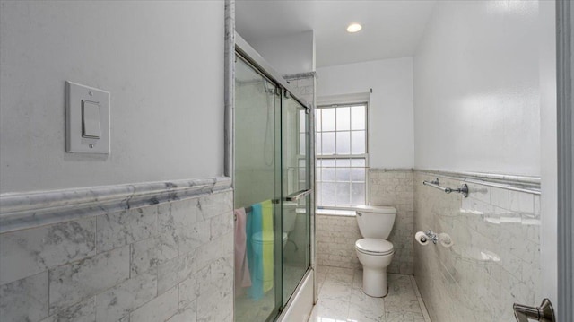 bathroom featuring walk in shower, tile walls, and toilet