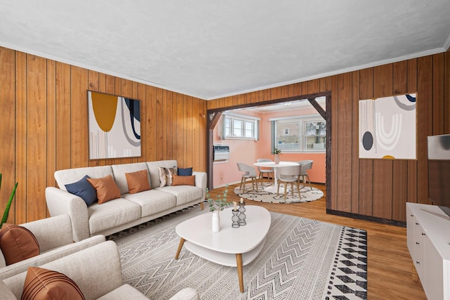 living room featuring ornamental molding, wood walls, and light hardwood / wood-style flooring