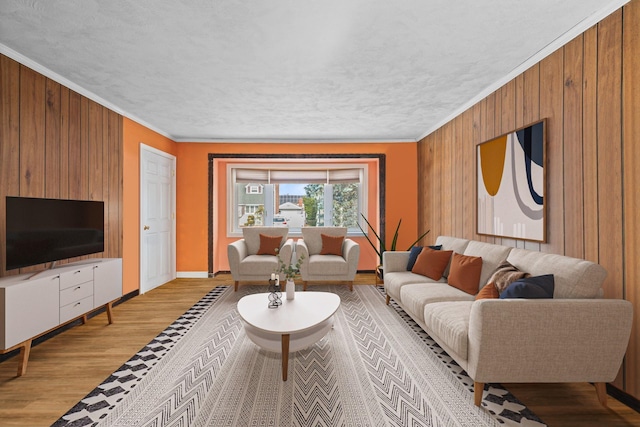 living room featuring crown molding, wooden walls, and light hardwood / wood-style flooring