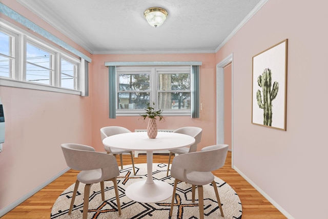 dining area with crown molding, light hardwood / wood-style flooring, and a textured ceiling