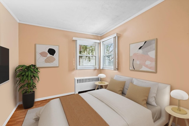 bedroom with hardwood / wood-style flooring, crown molding, and radiator heating unit